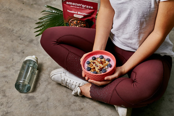 Amazin’ Graze granola and protein blends displayed with fresh fruit and oats for a balanced breakfast.