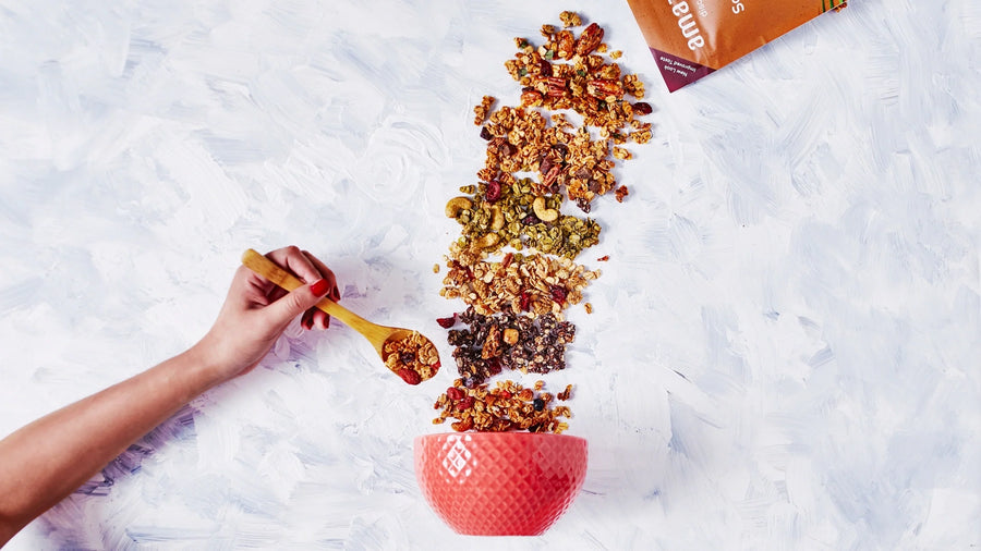  Amazin’ Graze granola being spooned into a small bowl for an easy, nutrient-dense meal.